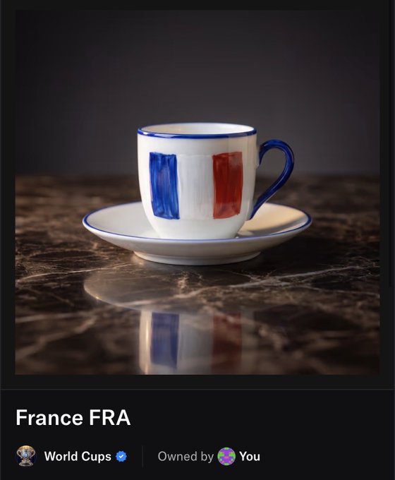 The image features a white cup with blue, red, and yellow stripes sitting on top of a brown table. The cup has a saucer underneath it, which matches its color scheme. The background appears to be black, making the colors of the cup stand out even more. In the bottom right corner of the image, there is text that reads "Let's go France @opensea", possibly indicating an event or promotion related to France.