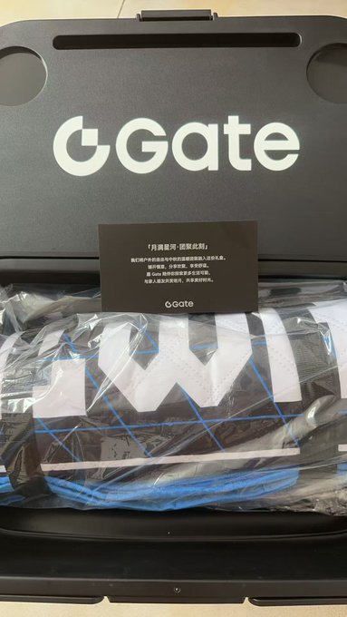 A "Gate" branded camping kit box is opened to reveal its contents, including a black card with Chinese text reading "「分典露营，摆脱低脂」" and a picnic mat in plastic packaging. The image aligns with the post by showcasing the camping gear received from Gate in preparation for a Mid-Autumn Festival moon-viewing gathering.