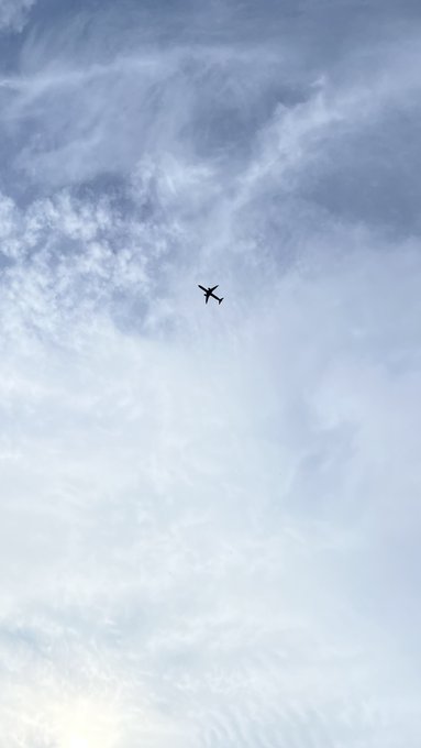 An airplane flying in a sky filled with wispy clouds.