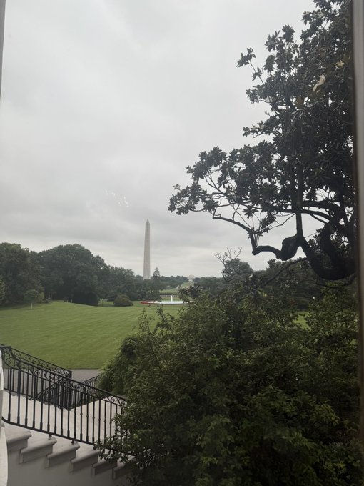A view from a balcony overlooking a lush green lawn with the Washington Monument visible in the distance under an overcast sky. The image doesn't directly relate to the crypto post about a potential airdrop and token distribution, though it could symbolize a free giveaway (airdrop) "falling from above."