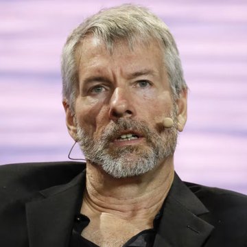 An older man with a gray beard, wearing a headset microphone and a black shirt, appears to be speaking at an event. The image likely depicts Michael Saylor, the Bitcoin advocate referenced in the post about Bitcoin's strength as an asset and its future growth potential.