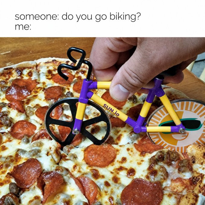 A meme with text 'someone: do you go biking? me:' showing a pizza cutter shaped like a yellow and purple bicycle with 'SUN.to' on the frame, being used on a pepperoni pizza.