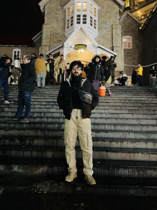 A man stands on the steps of the Postal Museum building at night, seemingly preparing for a departure as hinted by his companion's "See you tomorrow" caption.