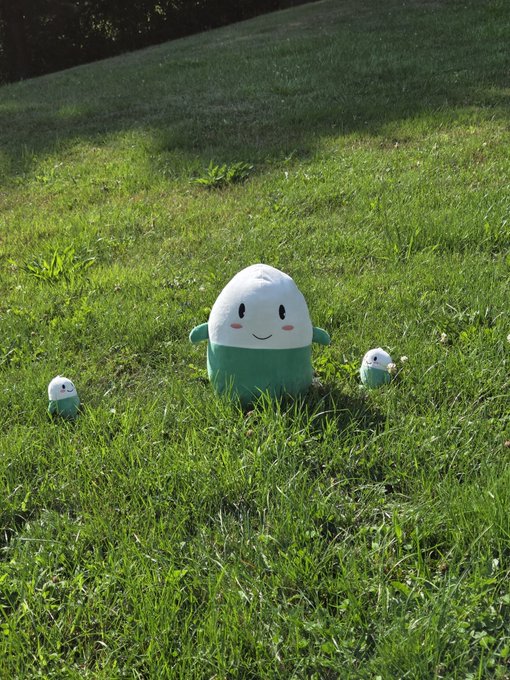 A family of three adorable plush toys—one larger Cupsey character in the center flanked by two smaller versions—sits together on lush green grass, mirroring the post's playful reference to "me and the little ones" enjoying time outside during a market dip.
