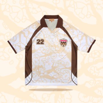 A white and brown short-sleeved sports jersey with the number "22" on the chest and a team crest, displayed against a beige patterned background.