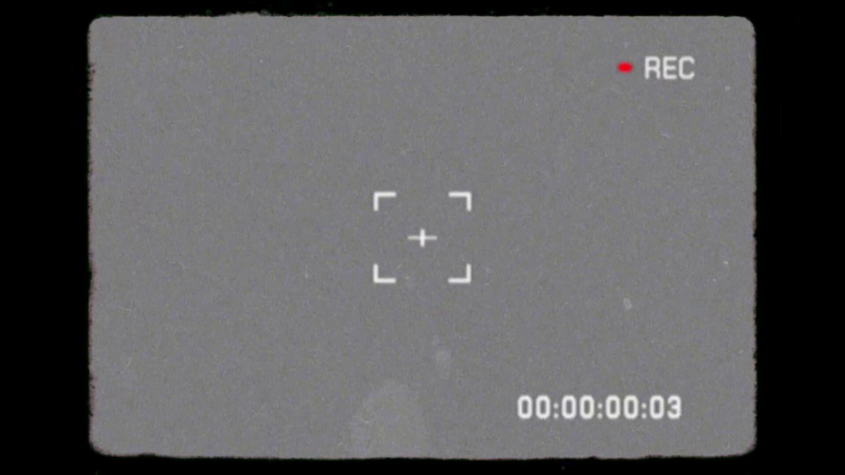 The image shows a screenshot of an electronic device, possibly a camera or a computer screen displaying a video feed with a red circle indicating that the recording is active. The background appears to be black, which contrasts with the white square frame on which the screenshot is displayed. There are no texts present in the image.