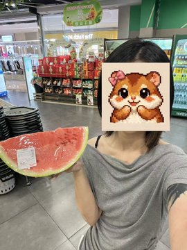 The image features a woman holding up a slice of watermelon with a cute cartoon hamster face on top of it. The woman has her hair tied back, and she appears to be posing for the photo. In the background, there are several chairs arranged in rows, suggesting that this might be taking place at an event or gathering.