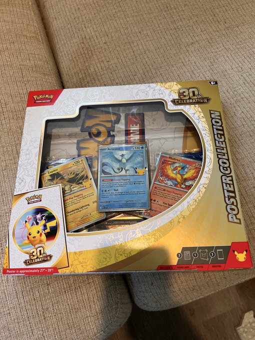 A Pokémon 30th Celebration Poster Collection box featuring Pikachu on the cover, sitting on a beige couch.