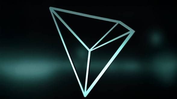 A glowing teal geometric logo featuring a stylized diamond or triangular shape is displayed against a dark background with soft lighting effects.
