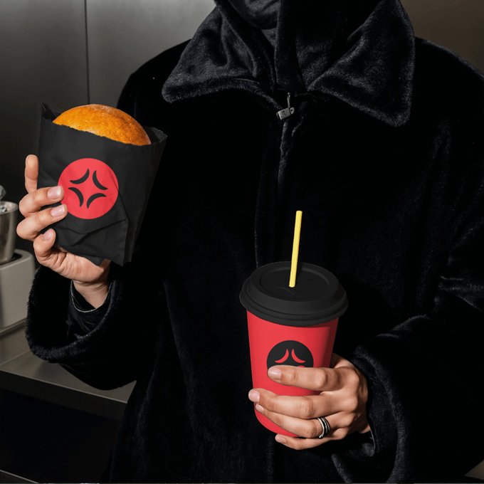 A person in a black coat holds a wrapped burger and a red drink cup, both featuring the distinctive Tabi logo, suggesting they're enjoying a quick meal on the go. The "See it. Want it. Tabi it." tagline reinforces the brand's convenient, craveable appeal highlighted in the image.