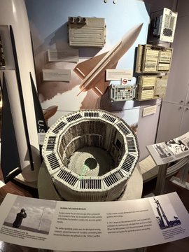 urn of water, rocket on wall, and information board display at a museum exhibit