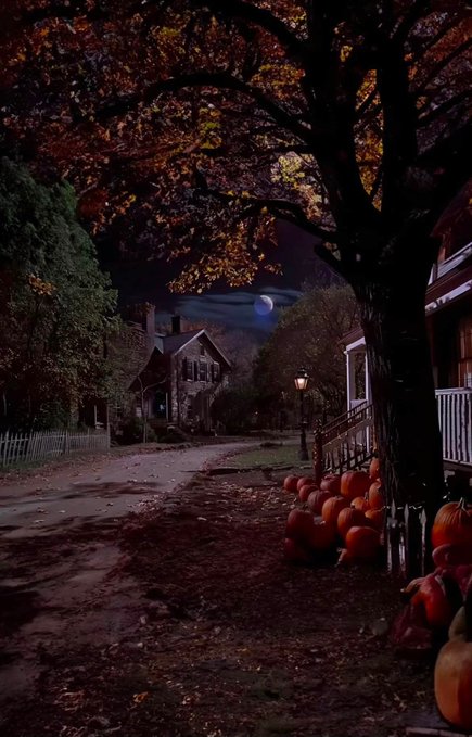 A moody autumn night scene with a crescent moon, featuring a stone house and a white house along a path lined with pumpkins and fall foliage under a large tree.