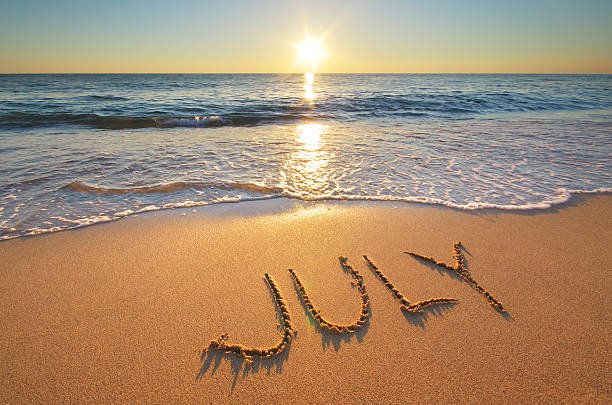 A serene beach at sunset with the sun reflecting on the water and the name 'JUNY' written in the sand.
