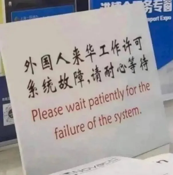 The image shows a white sign with Chinese characters that reads "Please wait patiently for the failure of the system." Below this message, there's an image of a clock showing the time as 12:00 pm (noon). The text on the sign is in Chinese and appears to be written in English.