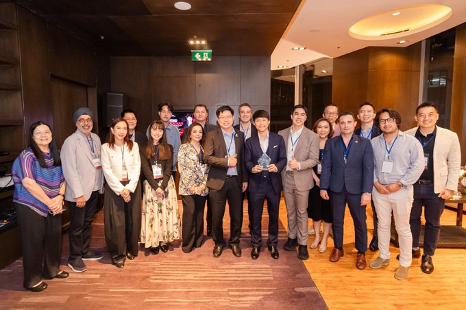 A group photo of professionals in business attire posing together at what appears to be a corporate or networking event.