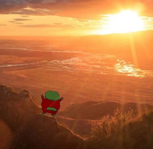 A scenic sunset landscape over a canyon with a small cartoon character with green hair and a red body standing on a cliff in the foreground.