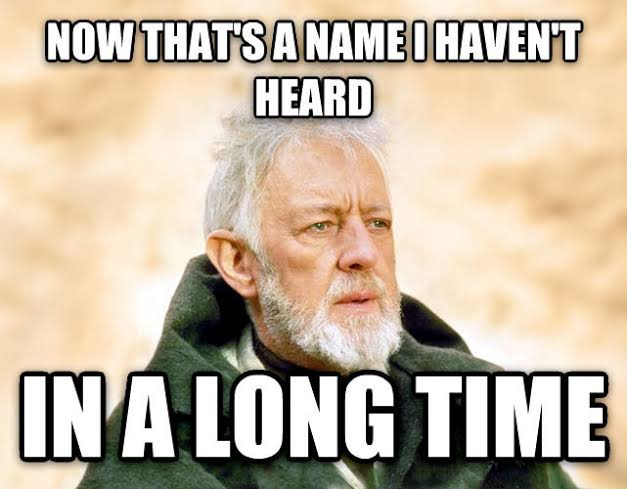 A meme featuring an older bearded man in a green cloak with the text 'NOW THAT'S A NAME I HAVEN'T HEARD' on top and 'IN A LONG TIME' on the bottom.