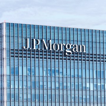 The image shows the upper facade of a modern glass-and-steel skyscraper featuring the "J.P.Morgan" logo prominently displayed, representing the financial institution referenced in the post about JPMorgan's warning regarding the CLARITY Act's impact on crypto markets and institutional adoption.