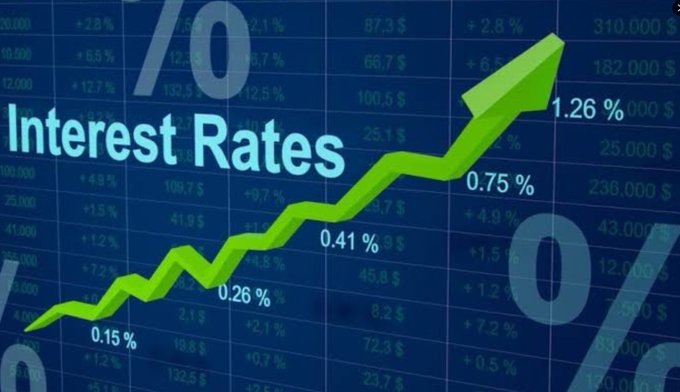 A digital graphic displaying the words "Interest Rates" with a green upward-pointing arrow over a background of financial data and percentages.