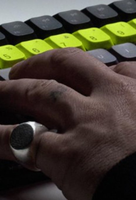 A hand wearing a silver signet ring rests on a keyboard with distinct yellow keycaps, with fingers positioned near the "A" and "3" keys—matching a small "a3" tattoo visible on one finger, seemingly a nod to the popular Robinhood ticker symbol referenced in the post.