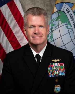 A formal portrait shows four-star U.S. Navy Admiral Samuel Paparo in dress uniform with extensive ribbon racks, standing in front of the U.S. flag and the U.S. Indo-Pacific Command seal, accompanying his statement about the military testing Bitcoin node operations for network security.