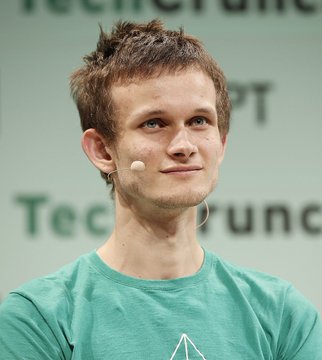 A young man with short brown hair, wearing a teal t-shirt and a small headset microphone, smiles slightly while speaking at what appears to be a TechCrunch event, with the "TechCrunch" logo visible in the background. The image likely depicts Vitalik Buterin, co-founder of Ethereum, delivering a talk about the network's new roadmap and quantum-safe upgrades.