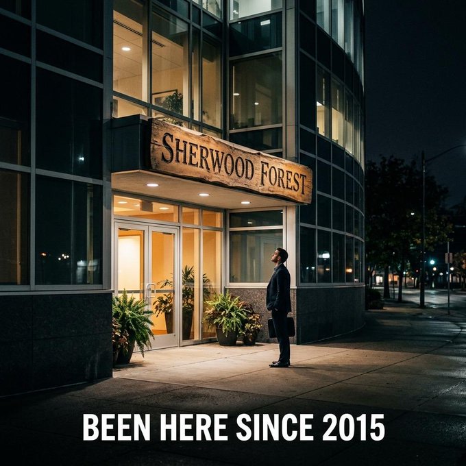 A moody nighttime photo of a businessman in a suit holding a briefcase, standing outside a modern glass building with a wooden 'SHERWOOD FOREST' sign above the entrance, with the caption 'BEEN HERE SINCE 2015' at the bottom.