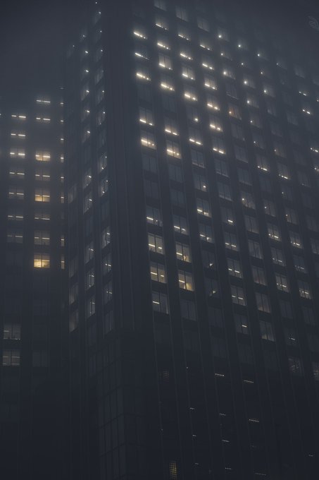 A tall building is photographed at night, with various windows illuminated against the dark exterior.