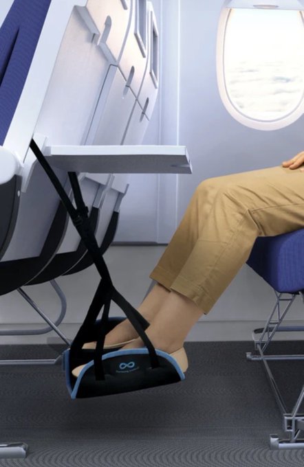 A passenger relaxes on an airplane, using a black foot hammock attached to the tray table of the seat in front to elevate their feet, creating extra legroom during the flight. 

The image cleverly plays on the post's caption—"Wen $BNKR hits a billy, there will be signs"—by visually showcasing the airline comfort accessory as a metaphorical "sign" of the $BNKR token reaching a billion-dollar milestone.