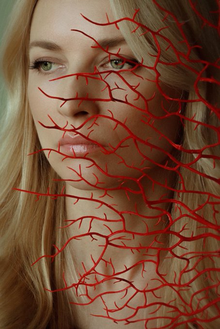 The image features a woman with blonde hair, wearing a necklace that has red branches attached to it. The woman's face is partially obscured by these branches, creating an interesting visual effect. The background of the image is blurred, drawing attention to the woman and her unique accessory. The caption at the bottom of the image reads "Happy Saturday! Veins Are Rivers", which could be interpreted as a reference to the red branches on the necklace or simply a playful way of describing the scene in the photo.

The image seems to be related to a post about veins, possibly discussing how they function and their importance in our bodies. The woman's choice of accessory might serve as an interesting visual representation of this concept, with the red branches symbolizing blood vessels carrying vital nutrients throughout our bodies.