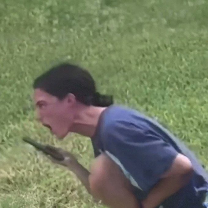 A woman with dark hair tied back, wearing a blue shirt, is bent forward while holding a phone to her mouth, set against a grassy field—her intense, locked-in posture humorously matches the post's caption about being extremely focused while talking to her boss on the phone.