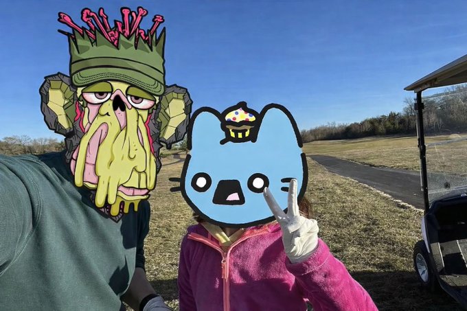 A selfie showing two people outdoors at what appears to be a golf course, with cartoon monkey and blue cat stickers covering their faces.