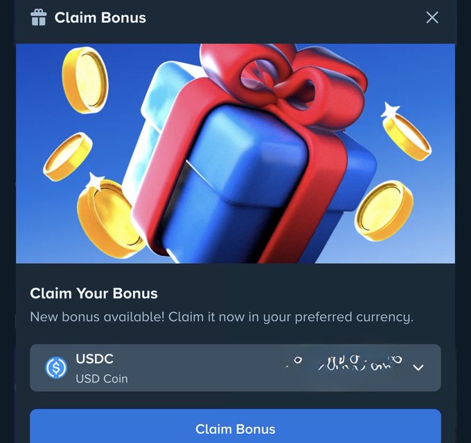 A mobile app pop-up window titled 'Claim Bonus' showing a 3D blue gift box with a red ribbon surrounded by gold coins, offering to claim a new bonus in USDC (USD Coin) currency.