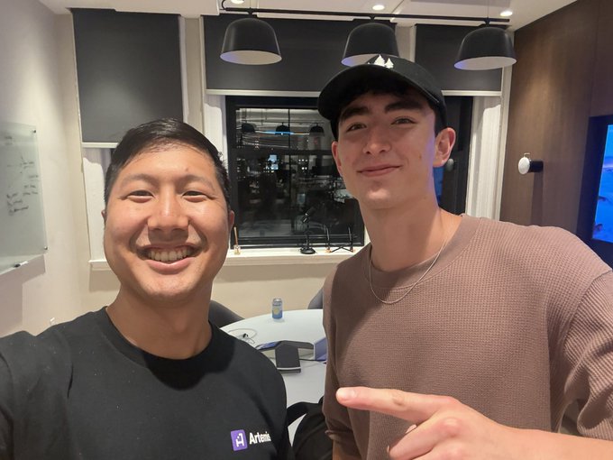 Two people pose for a selfie in what appears to be an office or meeting space, with one wearing a black "Artemis" branded shirt. The post caption references the Oregon Blockchain Club and tags @ev4nthompson and @chasneed_, though no identifying text or logos in the image clearly confirm the individuals' identities or connection to the club mentioned.
