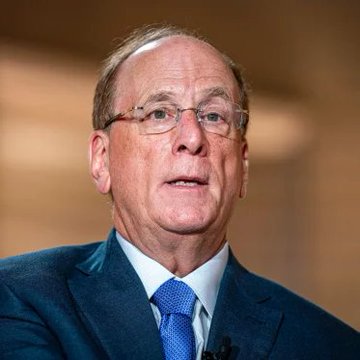 A portrait photograph of an older man wearing glasses, a dark suit, and a blue tie.