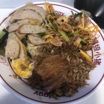 The image shows a plate of food with various ingredients, including meat, rice, vegetables, and eggs. The plate has a red rim around its edge, giving it an appealing appearance. The food appears to be well-cooked and ready to eat.