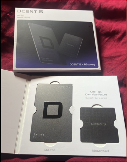 Two DCENT S Cold Wallet Cards are displayed in their retail packaging, featuring the sleek black cards with the prominent "D" logo alongside the R3covery backup card, as promoted in the giveaway post highlighting the wallet's one-tap NFC connectivity and EAL6+ security chip features.