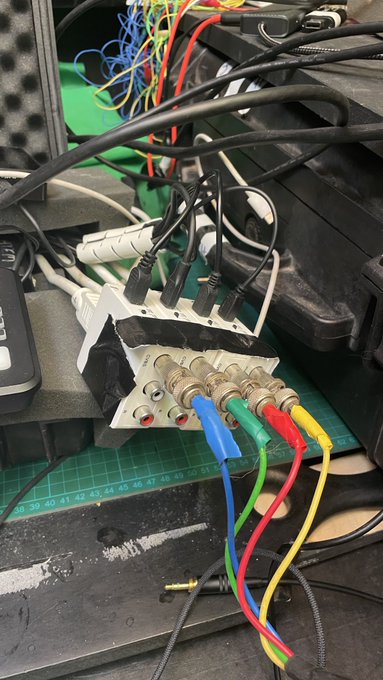 A workbench setup with exposed wiring, resistors with red, green, blue, and yellow leads, a power strip, and a cutting mat.