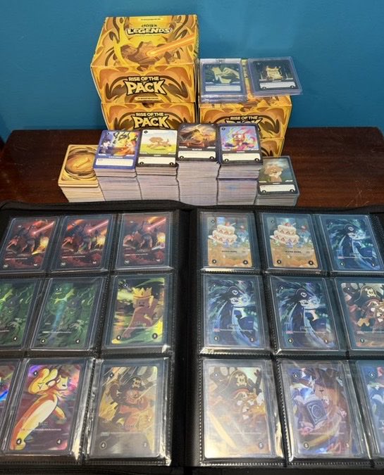 A collection of "Rise of the Floodborn" Disney Lorcana trading cards is displayed, featuring several unopened booster boxes and numerous sleeved cards in a binder, including characters like Stitch and Tamatoa.
