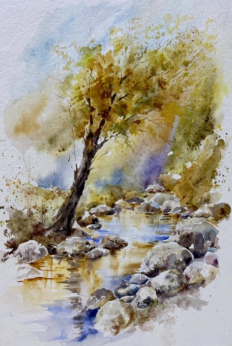A watercolor painting depicts a tree with autumn foliage standing beside a rocky stream, with stones and water rendered in loose, flowing brushstrokes.