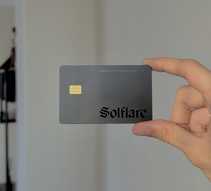 A hand holds up a sleek, credit card-sized Solflare hardware wallet, designed to look like an ordinary payment card with an embedded smart chip. This minimalist, cable-free design illustrates the post's point about a discreet, travel-friendly native Solana hardware wallet that doesn't resemble a typical crypto device.