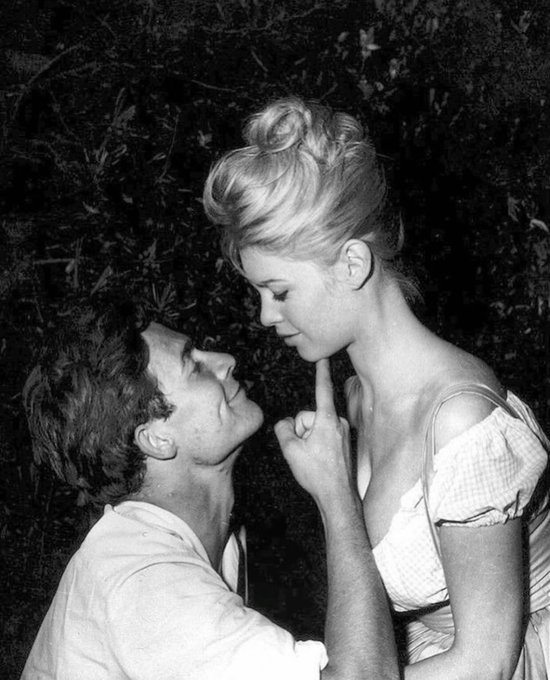 A blonde woman with a high updo and an off-shoulder dress gazes down at a man who looks up at her with his finger raised to her lips, in an intimate black-and-white moment. The classic romantic pose perfectly matches the post's "Yup" — a quiet affirmation of affection.
