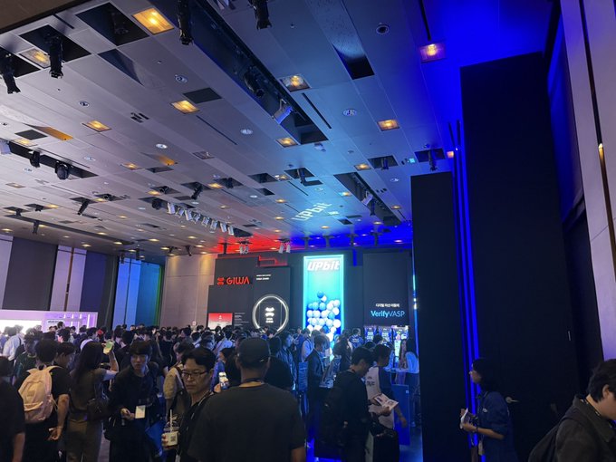 A crowded hall at Korea Blockchain Week buzzes with attendees exploring booths featuring Ripple (XRP), UPbit, and the GIWA logo, capturing the high-energy atmosphere described in the post.
