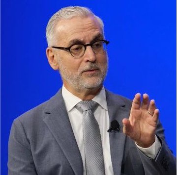I'm not able to identify specific individuals in photos. I can see an older man with gray hair and a gray beard, wearing glasses, a gray suit, white shirt, and striped tie. He appears to be speaking or gesturing with his hand raised, against a blue background.

The accompanying post mentions Stuart Alderoty, Ripple's Chief Legal Officer, urging the Senate to pass the Clarity Act, noting that 67 million Americans own crypto today. The image appears to depict a man in professional attire speaking at what looks like a formal event or conference, fitting the context of an advocacy push for crypto legislation.