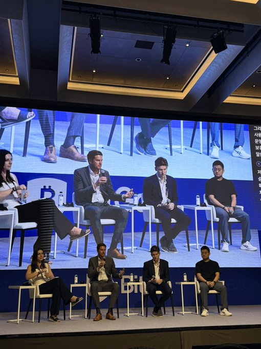 A group of five panelists sit on stage during a conference discussion, with a large screen displaying the "b1" logo behind them. The setup appears to complement the post's quote about launching your own blockchain chain, suggesting a fireside chat or panel debate focused on cryptocurrency and blockchain strategy.