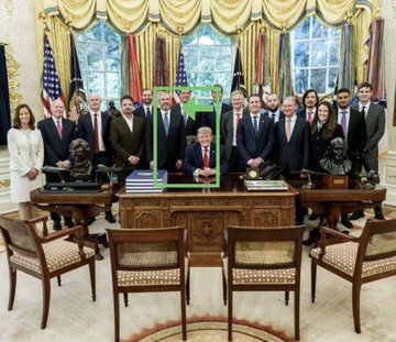 A formal group photo in the Oval Office featuring Donald Trump seated at the Resolute Desk with a group of officials standing behind him; Trump is highlighted by a green bounding box.