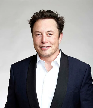 The image features a man wearing a suit jacket with a white shirt underneath. The man has short hair and a beard, giving him a distinguished appearance. He is smiling at the camera, exuding confidence and charm. In the background of the photo, there are two dollar signs, which could be related to the post's content about Elon Musk.