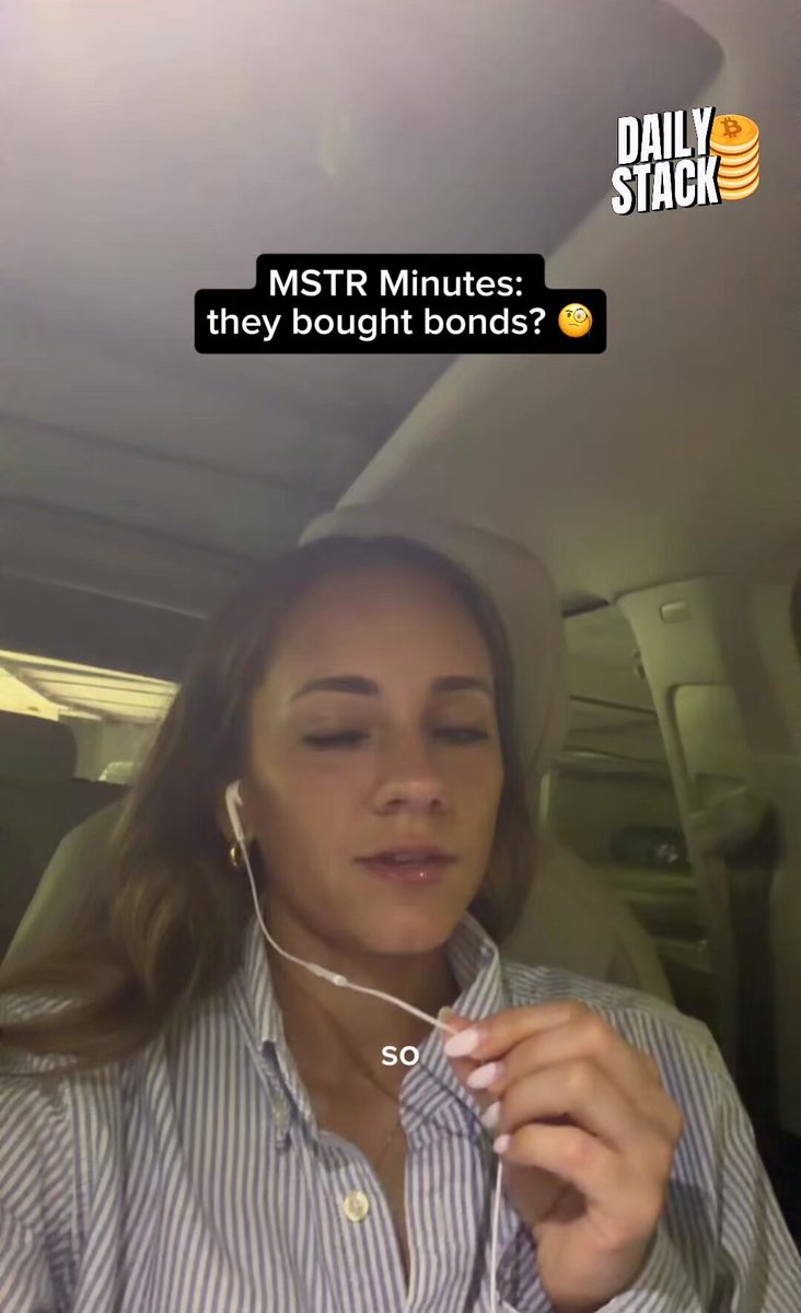 The image shows a woman wearing headphones while sitting inside a car. She appears to be listening to music or a podcast, possibly enjoying her time alone during a drive. The photo has been captioned with text that reads "Daily Stack" and "MSTR Minutes", which suggests it might be related to the stock market or financial news.