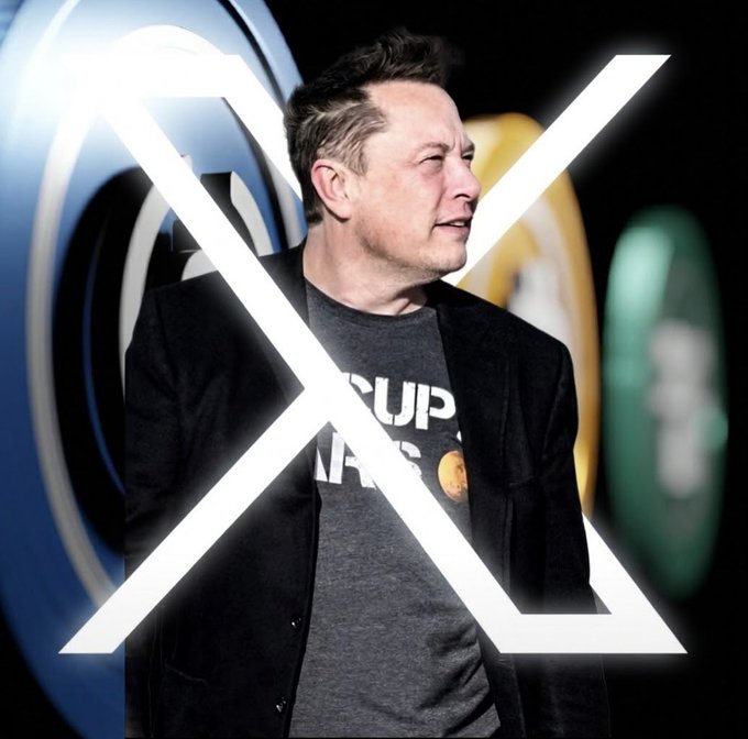 Elon Musk, wearing a dark blazer over a graphic t-shirt, stands in front of a large white X logo with colorful circular elements in the background.