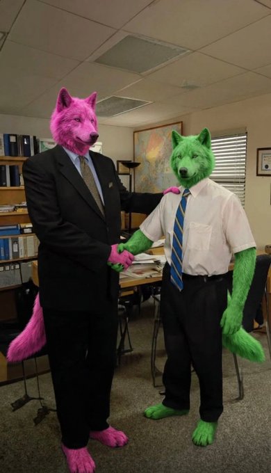 An image showing two people wearing furry animal head masks (one pink wolf-like, one green wolf-like) dressed in business attire (suits and ties) posing together in an office setting.
